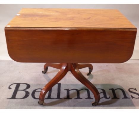 A George III mahogany ebony strung supper table, with hinged drop leaves and end drawer, ring turned pillar and quadripartite