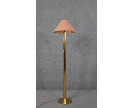 A brass standard lamp, with a salmon coloured shade, on a cylindrical stem with a circular base. H.143 Diam.38cm 