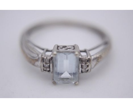 An aquamarine and diamond flanked solitaire ring. Set with an emerald cut aquamarine with an approximate weight of 0.79 carat