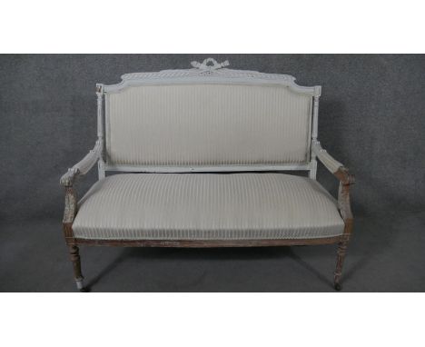 A French Louis XVI style canape sofa, the frame partially painted in light grey, the gadrooned back rail with a crossed torch