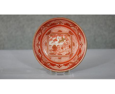 An 18th century Japanese red Kutani hand painted ceramic bowl. The centre decorated with figures under a tree and the outside
