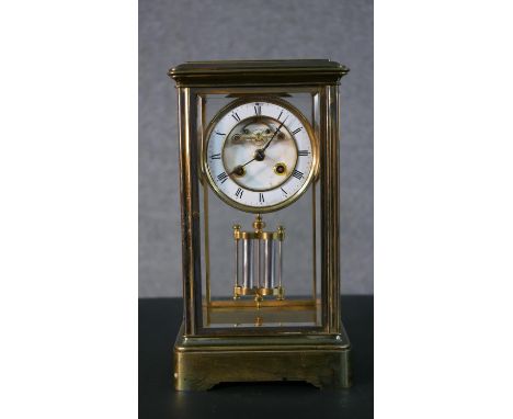 An early 20th century faux mercury pendulum brass and bevelled plate mantle clock, with white enamel dial with black roman nu