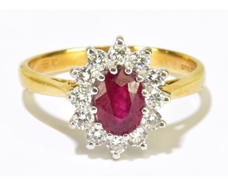 An 18ct yellow gold diamond and ruby floral cluster ring, the oval ruby set within a border of twelve diamonds totalling appr