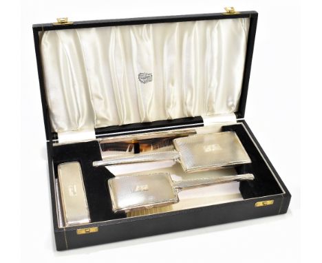 An Art Deco style silver four piece dressing table set, with engine turned detailing and each initialled 'HJB', Birmingham 19