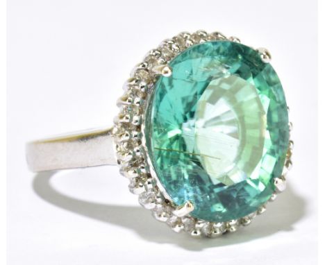 A 18ct white gold tourmaline and diamond cluster ring, the oval greenish blue four claw set tourmaline weighing approx 12.5ct