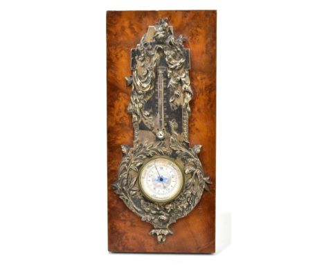 A Continental white metal aneroid barometer/thermometer, with circular dial and cast floral detail, mounted in a later burr w