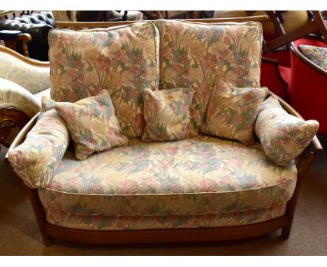 ERCOL; a modern dark elm framed two-seater sofa and matching armchair (2).