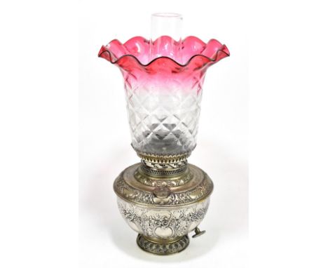 NEW ROCHESTER; an American silvered metal oil lamp with repousse decoration with clear cranberry coloured shade, overall heig