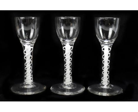 Three wine glasses with fluted bowls raised on double opaque air twist stems terminating on conical bases, height 14cm.&nbsp;