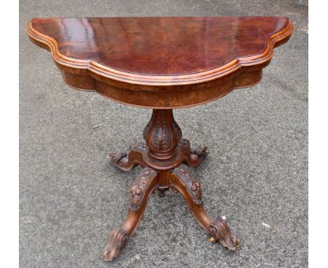 A Victorian burr walnut serpentine fronted fold over card table, with green baize lined interior, on a carved baluster column