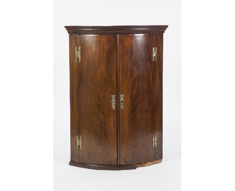 GEORGE III FLAME CUT MAHOGANY BOW FRONTED CORNER CUPBOARD, of typical form with moulded cornice, brass 'H' hinges and three s