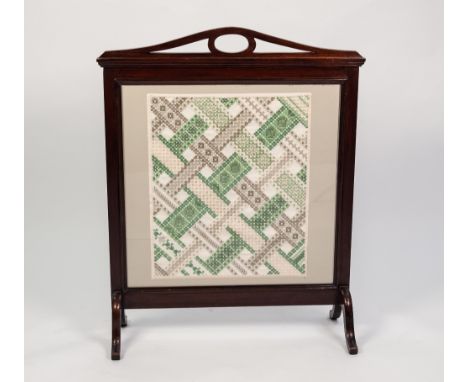MAHOGANY STAINED FIRESCREEN, with pierced top rail and glazed central panel worked in coloured and pulled threads with diagon