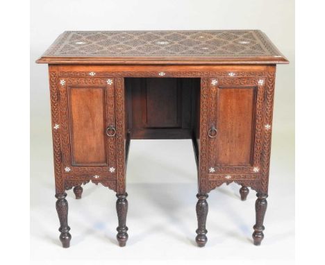 An early 20th century Moorish style carved hardwood kneehole desk, with a parquetry top, on turned legs. Note: a non-transfer