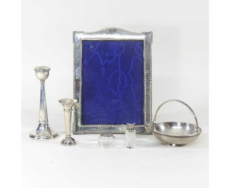 A silver photograph frame, Birmingham 1907, 26 x 20cm overall, together with a candlestick, silver spill vase, enamel top sce