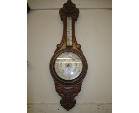 Early 20th Century carved oak aneroid barometer thermometer with silvered dials (thermometer at fault), 35ins high 