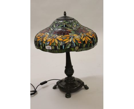 Reproduction Tiffany style table lamp, the leaded glass floral design shade above a dark patinated metal body and quadruped b