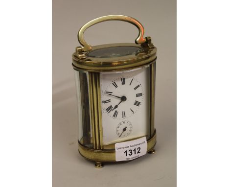 Late 19th / early 20th Century French brass carriage clock, the oval case enclosing an enamel dial with Roman numerals and su