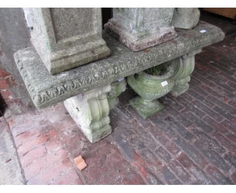 Weathered cast concrete garden bench on shaped supports, with vine decoration 