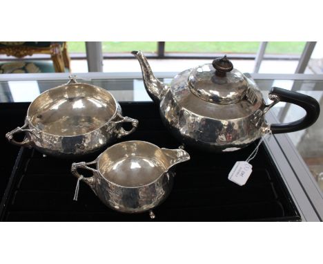 An Edwardian Arts and Crafts Sterling silver three piece tea service, the handles with stylised Tulip terminals, hand hammere