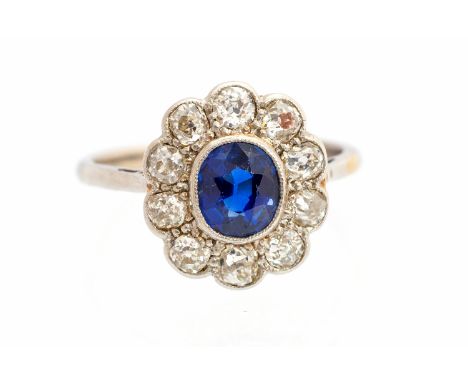 A sapphire and diamond oval cluster white gold ring, central oval swiss-cut blue sapphire approx 1 carat, rub-over set, ten r