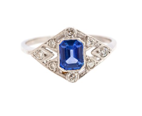 An Art Deco style sapphire and diamond platinum ring, the central step-cut blue sapphire approx 0.85 carat, surrounded by rou