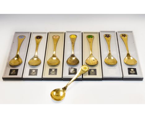 Eight Georg Jensen sterling silver-gilt year spoons from 1973 to 1980 &amp; 1984, each with a floral enamel motif at the term