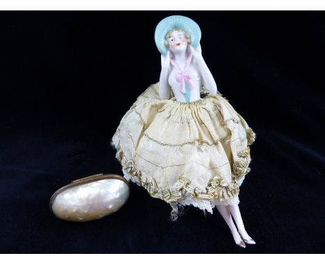 Early 20th century pin doll with pin cushion base, skirt, ceramic body and legs and a shell needle / pin box