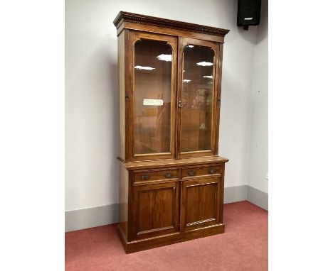 An Early XX Century Mahogany Bookcase, the top with dentil cornice over twin glazed doors, the base with two small drawers ov