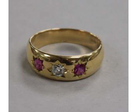 An 18ct gold, three stone ruby and diamond gypsy set ring, size U.