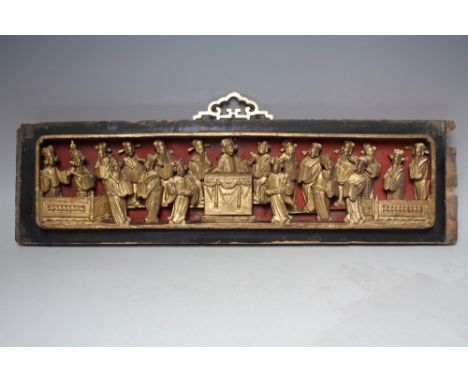 AN ORIENTAL CARVED AND GILT WOOD RECTANGULAR PANEL, modelled as figures carved in relief around a central figure, later gilt 