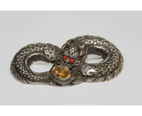 A VINTAGE WHITE METAL CHINESE DRAGON TYPE BROOCH, set with a citrine style stone by the mouth and two coral type eyes, W 8.5 