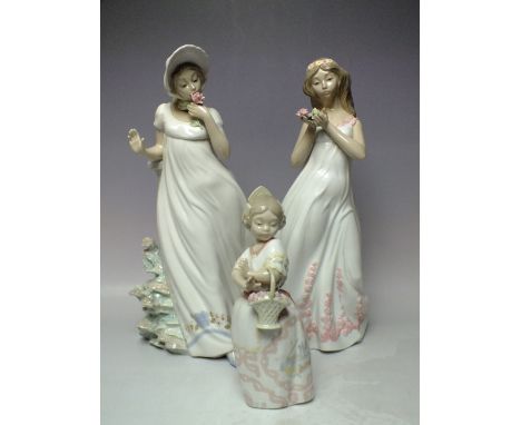 TWO LARGE NAO FIGURES OF YOUNG GIRLS IN COSTUME HOLDING FLOWERS, tallest H 33 cm, together with a smaller flower (3)
