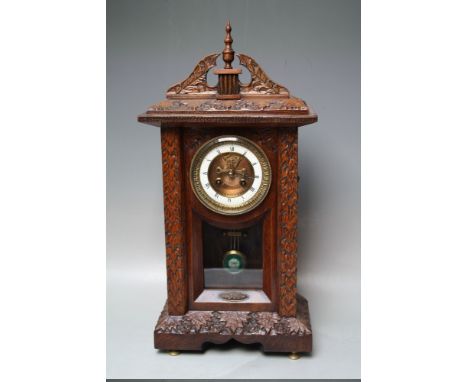 A LATE 19TH CENTURY CARVED OAK MANTEL CLOCK, the enamel dial with Roman numerals, visible anchor escapement and finely turned