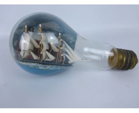 Small diorama of a three masted clipper passing a Lighthouse in a large glass light bulb, L22cm   Condition Report   Click he