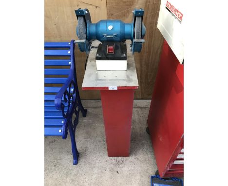 A TWO WHEELED BENCH GRINDER MOUNTED ON A METAL STAND - SOLD IN WORKING ORDER 