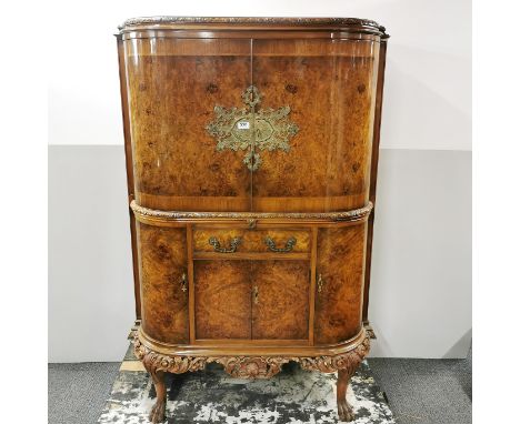 A carved and burr walnut veneered drinks cabinet with mirrored interior and cocktail slide by Berick Furniture, 155 x 100 x 5