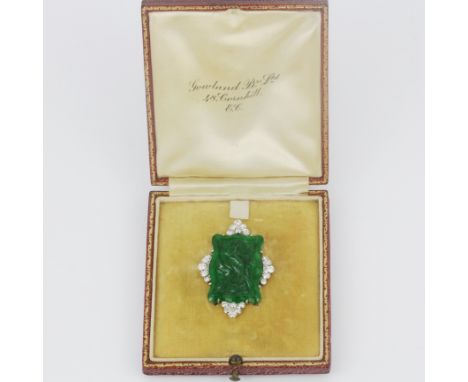 A 1920's white metal mounted (tested minimum 14ct gold) carved Burmese jade double pinned back brooch set with old cut diamon