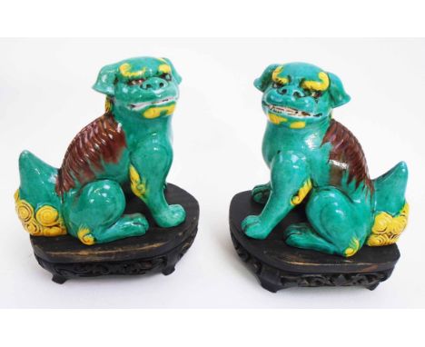 PAIR OF CHINESE CERAMIC BUDDHISTIC LIONS, green glaze with coloured detail, each 10cm L x 10cm H; together with wooden stands