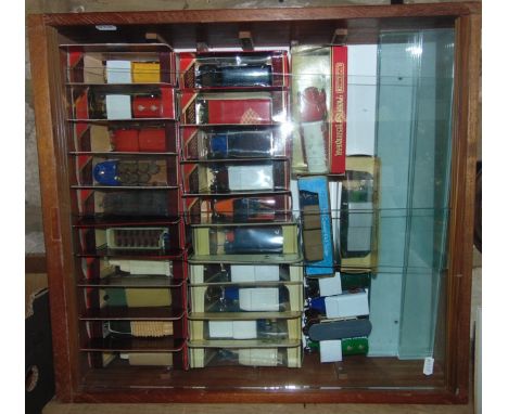 A wall hanging timber display shelf with sliding glazed doors containing a quantity of boxed die cast model vehicles to inclu