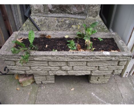 A weathered cast composition stone flower trough of rectangular form with raised foliate detail (planted) together with one o