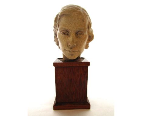 A finely worked ceramic head of a young woman, mounted on a timber plinth