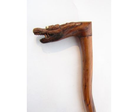 An unusual eastern hard wood walking stick of waved form terminating in a carved handle in the form of a dragons mask