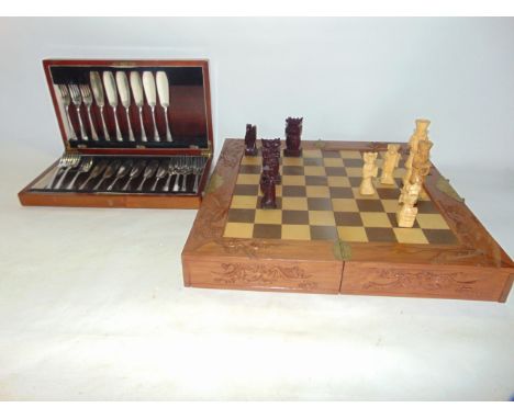 A Chinese timber chess set, the carved hinged base with detail depicting bats opening to reveal a chess board, each side with