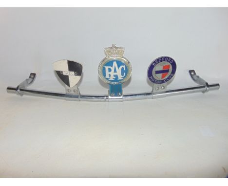 A 20th century chromium automobile bumper grill accommodating three motoring badges, centrally the RAC with white script upon