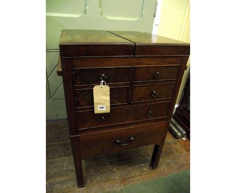 A Georgian mahogany gentleman's fold over top washstand over an arrangement of a cupboard enclosed by four simulated short dr