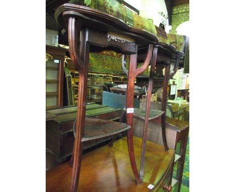 A pair of Art Nouveau walnut two tier occasional tables, tri-form with moulded outline raised on tapered swept and moulded tr