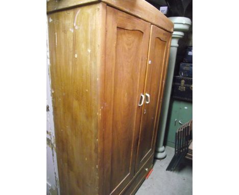 A vintage European pine wardrobe enclosed by a pair of three quarter length shaped panelled doors over a long drawer to base,