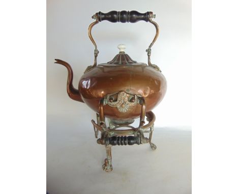 A heavy antique copper kettle raised on associated stand with turned ebonised timber handles, the kettle with a ceramic finia