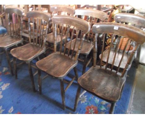 A set of seven Windsor elm and beechwood stick back kitchen chairs with saddle shaped seats, raised on ring turned and tapere