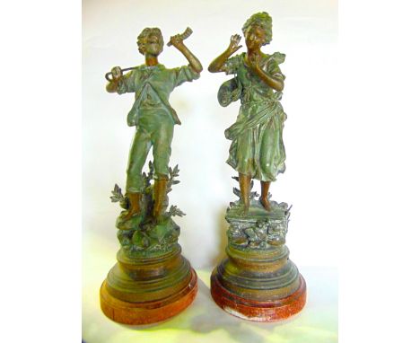 A pair of French painted spelter sculptural figures, one depicting a boy playing a horn, the other a young girl gesturing to 